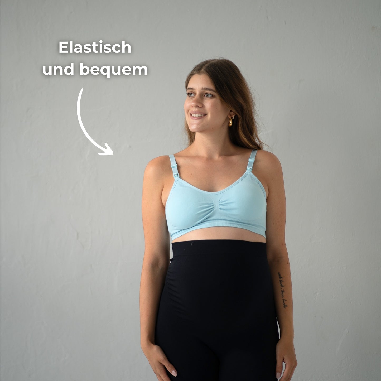 Das Bild zeigt eine werdende Mutter, die einen blauen Still-BH trägt. Sie steht in einer entspannten Haltung und lächelt, während sie den BH präsentiert. Der Text „Elastisch und bequem“ ist neben ihr positioniert, um die Flexibilität und den Tragekomfort des BHs hervorzuheben. Der Hintergrund ist neutral und lässt die Mutter und den BH im Fokus stehen.